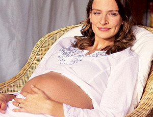 Беременная женщина сидит в плетеном кресле