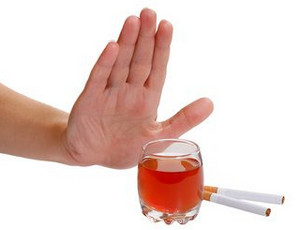 Рука перед стаканом с алкоголем и сигаретами