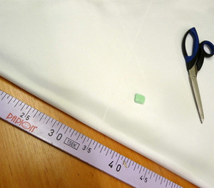 Сложенная белая ткань, сантиметр и ножницы